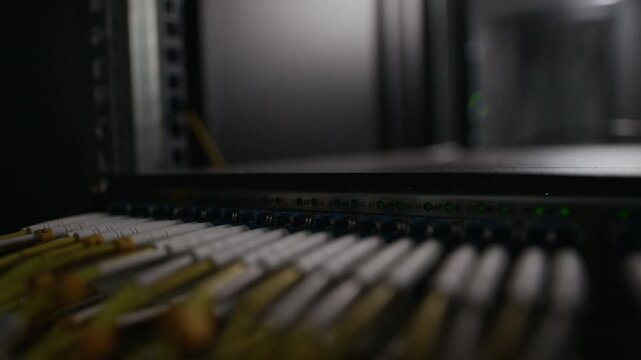 Extreme close up macro of ethernet cables connected to network switch with blinking status lights inside server rack