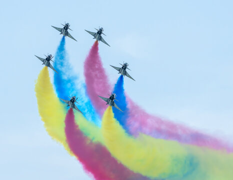 Aerial view of fighter jets soaring through the sky, painting vibrant trails of blue, red, and yellow against the pale canvas above, Changi Exhibition Centre, Singapore Air Show 2026, Singapore.