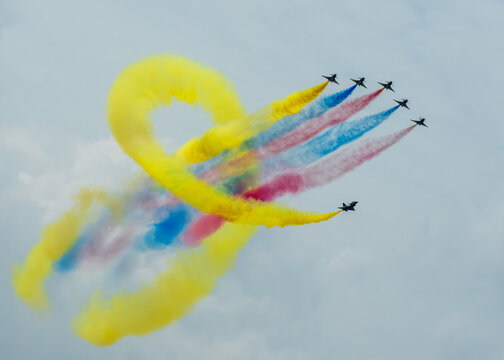 Aerial view of planes soaring through the sky, painting vibrant trails of yellow, red, and blue smoke, Changi Exhibition Centre, Singapore Air Show 2026, Singapore.