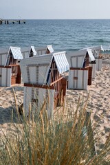 Fototapeta premium Strandkorb lined on sandy Rugen beach by Baltic Sea with pier in background