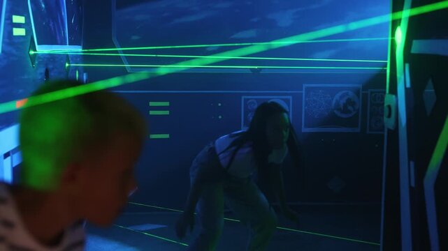 Girl and boy playing a laser labyrinth simulation game. Interactive adventure room.