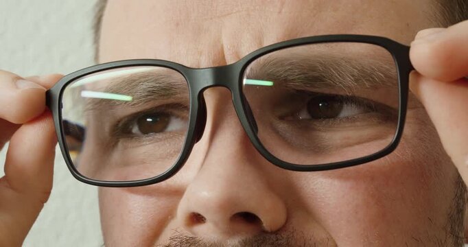 Close-up of a man adjusting eyeglasses with anti reflective lenses.