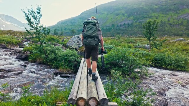 A Hiker Crosses a Small Wooden Bridge With a Dog Over a Mountain Stream in Sandland, Loppa Municipality, Finnmark, Norway - Tracking Shot