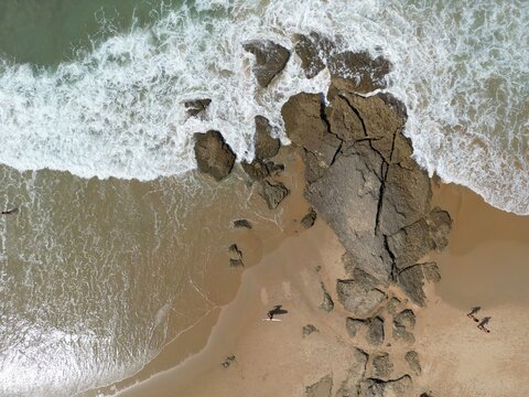 Aerial view of the jagged rocks meeting the foamy embrace of the Atlantic, creating a mesmerizing dance of textures and tones, Barbate, Andalusia, Spain.