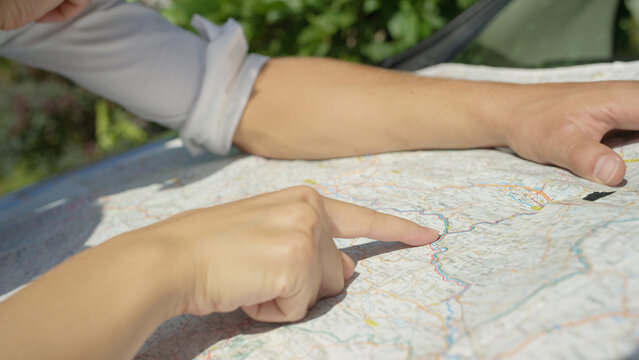 CLOSE UP: Unrecognizable young man and woman plan route of journey on the map
