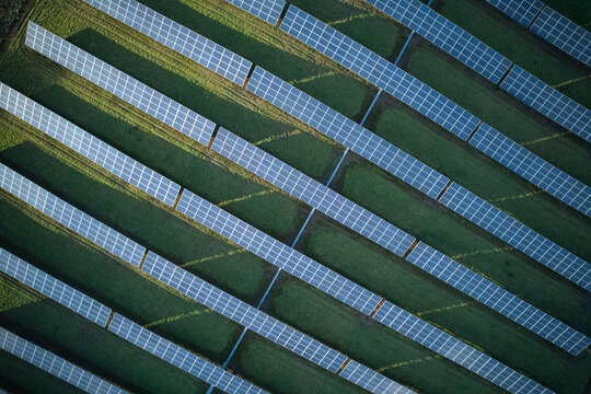 Aerial view of solar panels arrayed in neat rows across the verdant landscape, capturing sunlight with their dark surfaces, Stoke-on-Trent, England, United Kingdom.