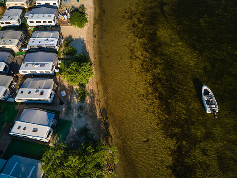 Aerial view of a motorboat anchored in the shallow waters of Puck Bay next to a coastal caravan campsite, Chalupy, Hel Peninsula, Pomerania, Poland.