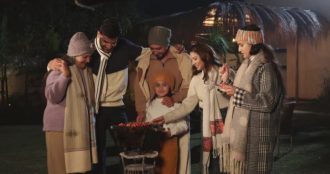 Indian happy mature adult female male speak share gossip enjoy winter cold have fun joy night outdoor garden place mom girl child kid talk with young man cook party food on barbecue spend quality time