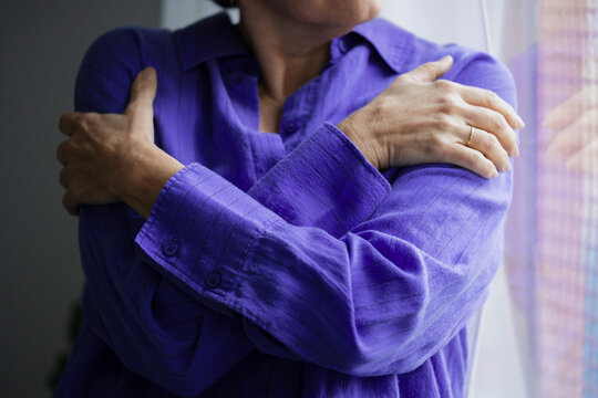 Woman wearing purple shirt holding shoulders to alleviate pain