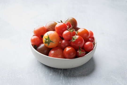 Fresh regional tomatoes in a bowl on light studio background