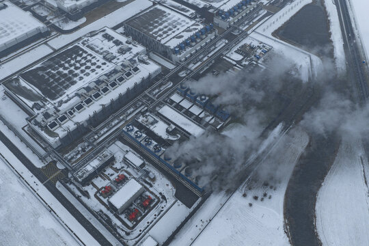 Aerial view of a large data center and industrial complex, operating in winter, showing cooling towers releasing steam, Eemshaven, Netherlands.