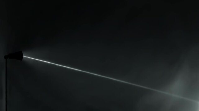 Spotlight beam cutting through dark space. Narrow ray of bright light shining in total darkness. Dramatic illuminated path in black background for design effect.