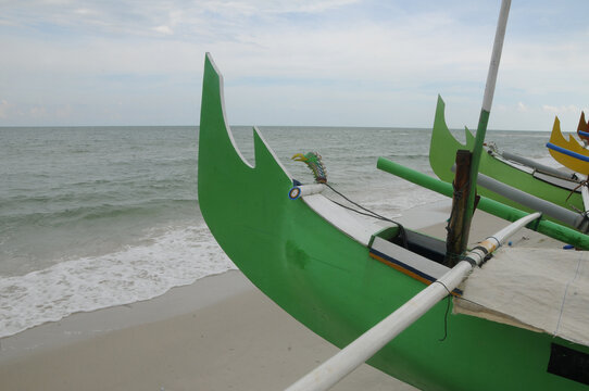 Bow of traditional wooden boats overlook the ocean on Serdang Beach in Belitung Island, Indonesia. 