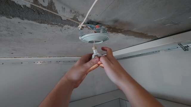 Hands attaching ceiling light fixture base during installation