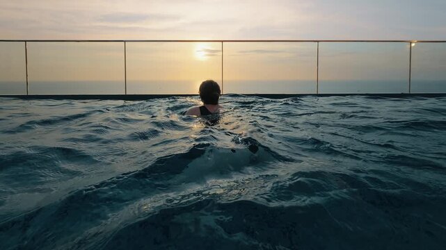 POV swimming in rooftop infinity pool at sunset overlooking ocean