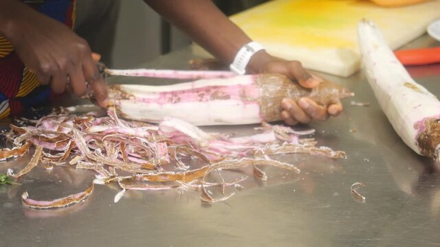 African chef prepares traditional cassava root for cooking in professional kitchen