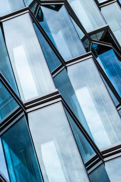 Abstract geometry in modern architecture as blue glass facade catches reflections and sharp angles create a bold pattern from below