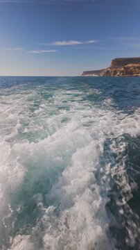 Slow motion vertical view from the stern of the ship of the foaming water flowing from under the ship propeller
