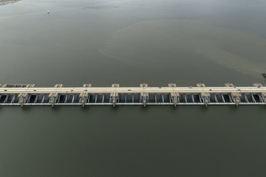 Aerial view of the Haringvlietdam stretching across the water, its concrete structure a stark contrast to the surrounding dark water, Haringvlietdam, South Holland, Netherlands.