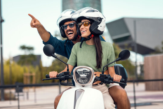 Couple enjoying city adventure riding scooter outdoors with helmets