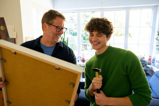 Father and son bonding at home while hanging a picture frame
