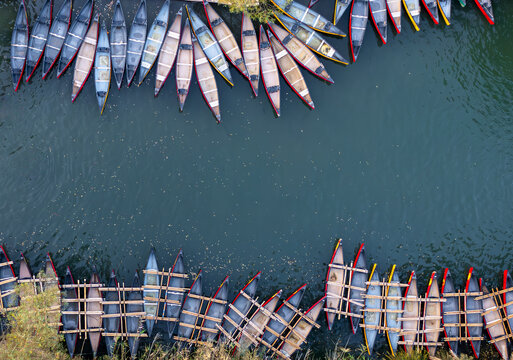 Aerial view of vibrant canoes lining the serene waters edge, their colorful hulls a stark contrast to the deep blue, Kineret, Israel.