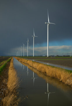 Wind turbines and canal under stormy snowclouds in Middenmeer Netherlands