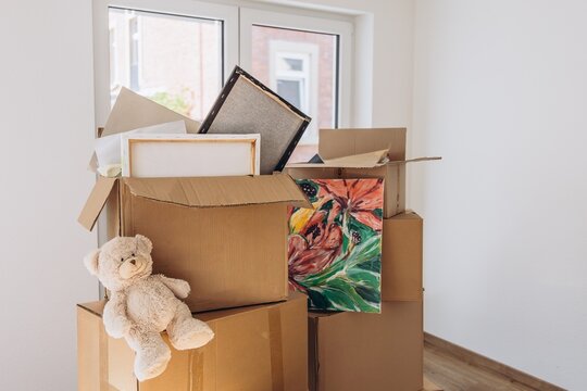 Stacked moving boxes with household items in an empty new home