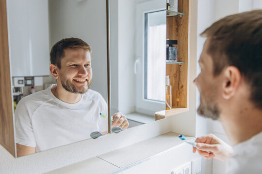 Father brushing teeth in bathroom mirror during morning routine