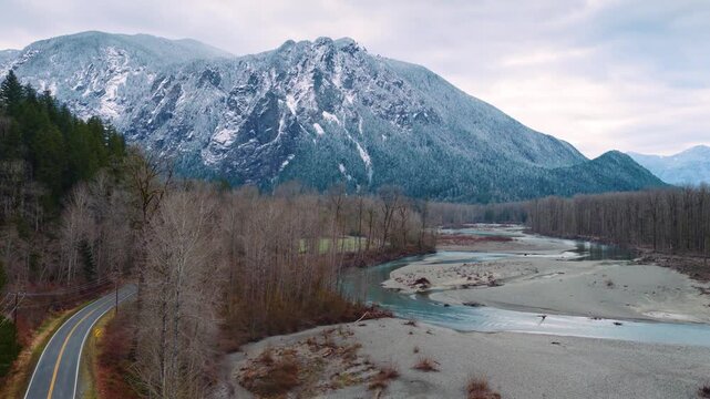 Scenic aerial of Mount Si with snow, river, and evergreen trees. Perfect for winter or outdoor travel content.