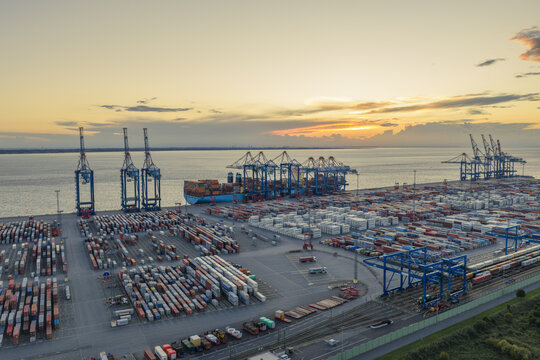 Aerial view of the sprawling container port with cranes silhouetted against the setting sun, a tapestry of industry and sky, Bremerhaven, Bremen, Germany.
