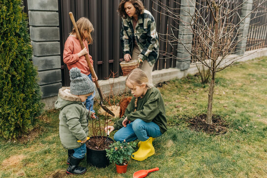 Family and children gardening together in backyard during spring