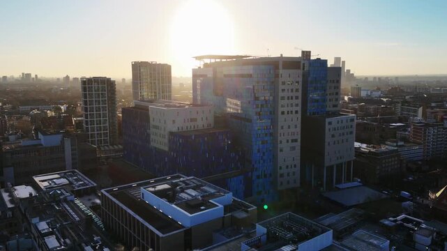 A rising backward aerial view of a modern hospital building at dawn.