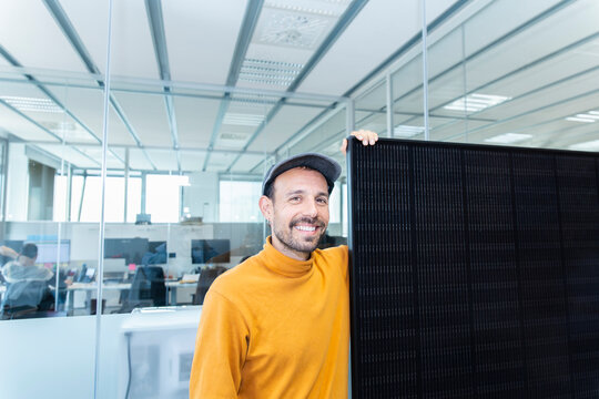 Client holding solar panel in modern office promoting renewable energy