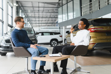 Fototapeta premium A consultant at a car dealership helps a customer choose a new car