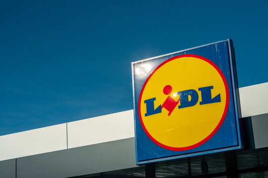 Characteristic Lidl store logo on the building facade, blue and yellow supermarket advertising sign against clear sky, outdoor branding of a grocery market, modern store exterior in bright sunlight.