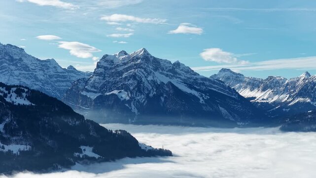 Snow covered alpine peak rising above thick cloud inversion in Walensee mountain valley, Switzerland