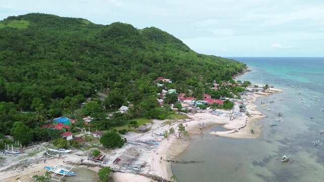 Aerial drone view of Scallop Beach on Guimaras Island Philippines showing tropical water and scallop shell shoreline. Scenic island coast surrounded by lush vegetation and peaceful seaside.