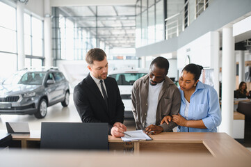 Car salesman helping couple choosing new vehicle in dealership