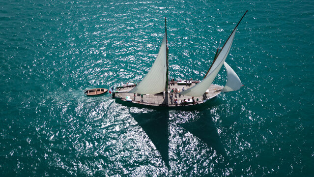Yvoire, France - 27 July 2024: Aerial view of a traditional sailing boat cutting through the turquoise waters of Lake Geneva, sails billowing in the wind, reflecting the sunlight.