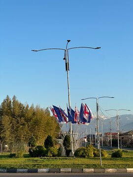 Georgian and European Union flags on roadside under clear blue sky, European integration, diplomacy, international relations, democracy concept, copy space.