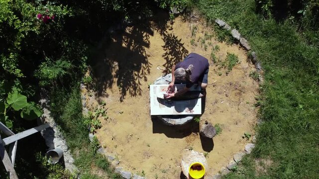 Aerial top down view of an active senior fisherman cleaning a large trophy catfish on a board outdoors