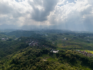 Obraz premium Dramatic sun rays breaking through clouds over the misty valley of Mount Lawu slopes.