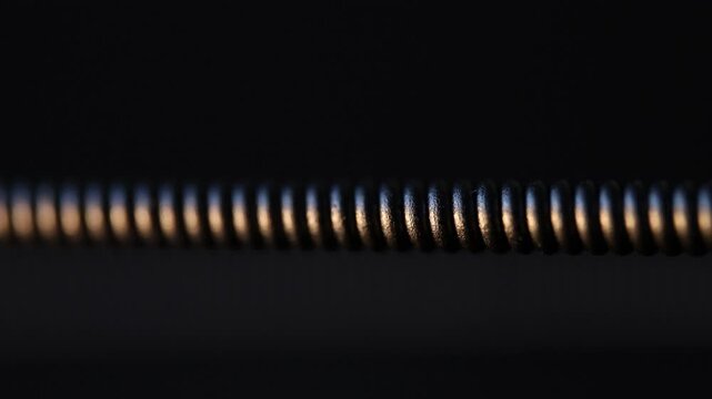 Macro vibrating guitar string with glowing reflections on dark background
