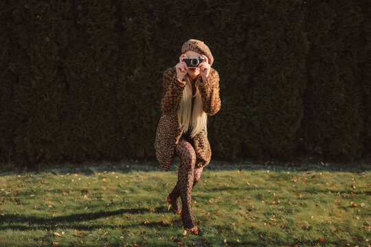 Fashionable woman in leopard print posing with camera outdoors