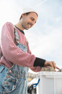 Customer browsing vinyl records at flea market smiling outdoors