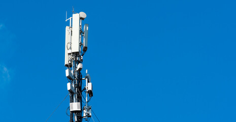 Cell tower stands tall against a clear blue sky in an urban area during daytime