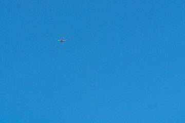 A distant airplane crossing a clear summer sky. Symbol of modern travel, international connections, and global tourism.