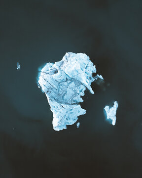 Aerial view of a stark, jagged iceberg floats in the frigid, dark waters, showcasing nature's raw beauty, Sveitarfelagid Hornafjordur, Iceland.