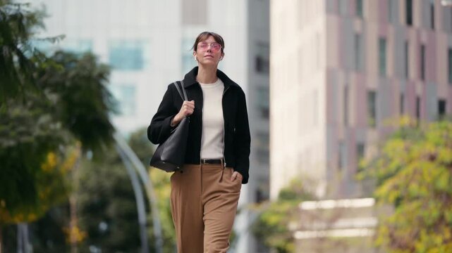Video of elegant woman listening music with earphones while walking across the city